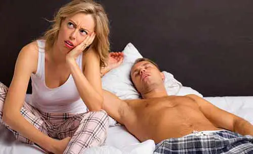 mujer aburrida con hombre en la cama