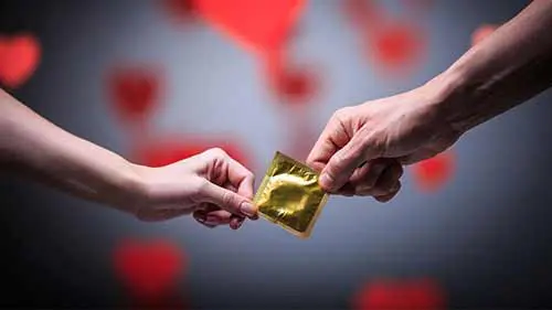 manos compartiendo preservativo